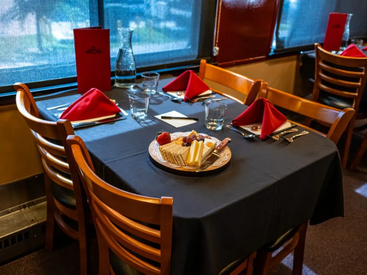 Table set for four with a cheese platter and red napkins by the window.