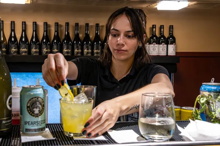 Bartender garnishing a cocktail with lemon slice in a bar.